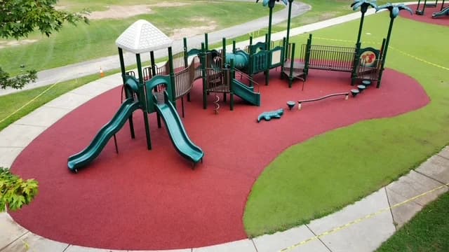 Red poured rubber play area with green slides and a contrasting green section